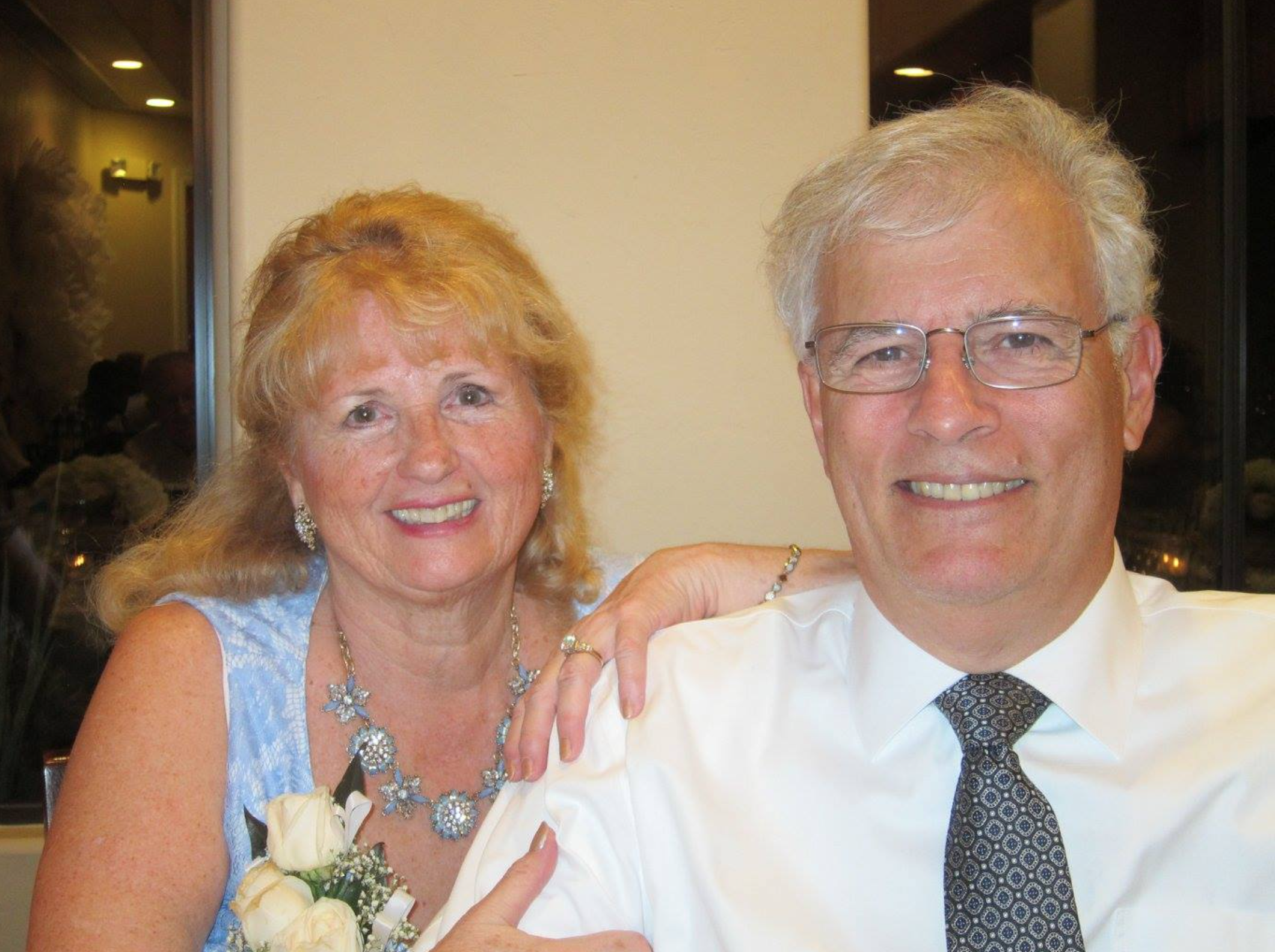 Karen and Bill Poulos sitting at a table at a wedding. 