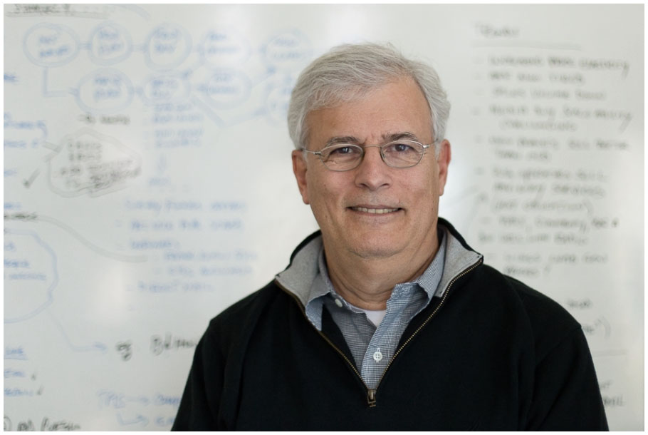 Bill Poulos standing in front of a white board.